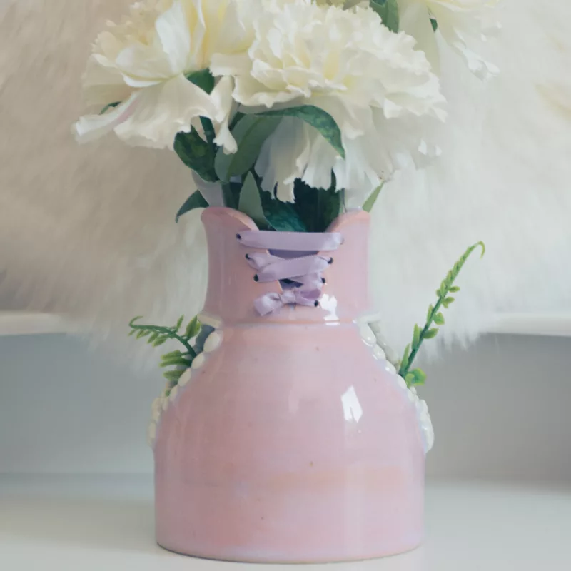 Vase en grès et porcelaine blanche, orné d'un lacet de satin violine, contenant des fleurs blanches