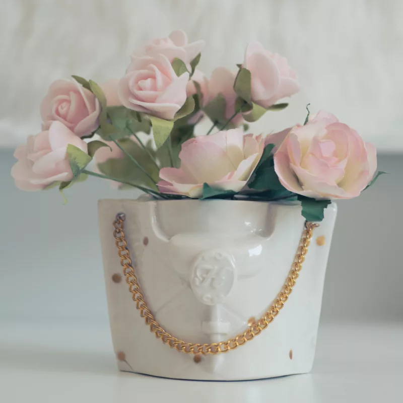 Mini Tasse en porcelaine blanche, luxueuse, avec un aspect capitonné, orné d'une bandoulière en métal doré, présenté avec des fleurs rose pastel