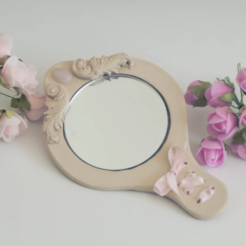 Mini miroir en céramique, orné d'un lacet de satin rose, avec quelques fleurs rose autour